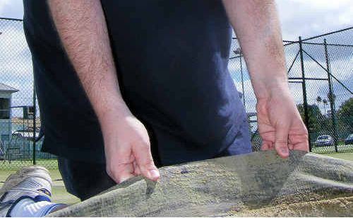 Warwick and District Tennis Association president Nathan Costello examines court flood damage.